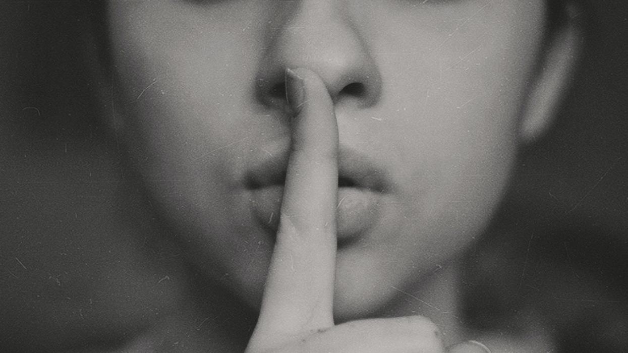 Woman shushing camera by putting a finger to her lips