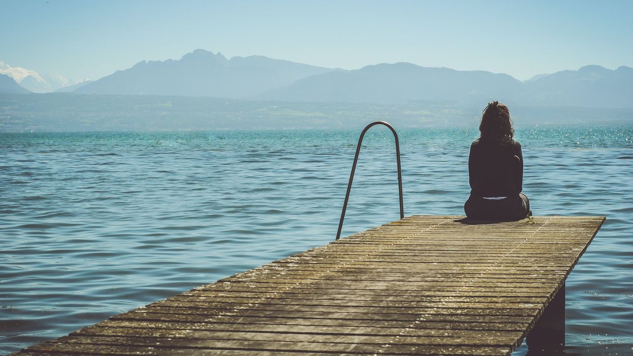 Woman sitting alone at the edge of a dock