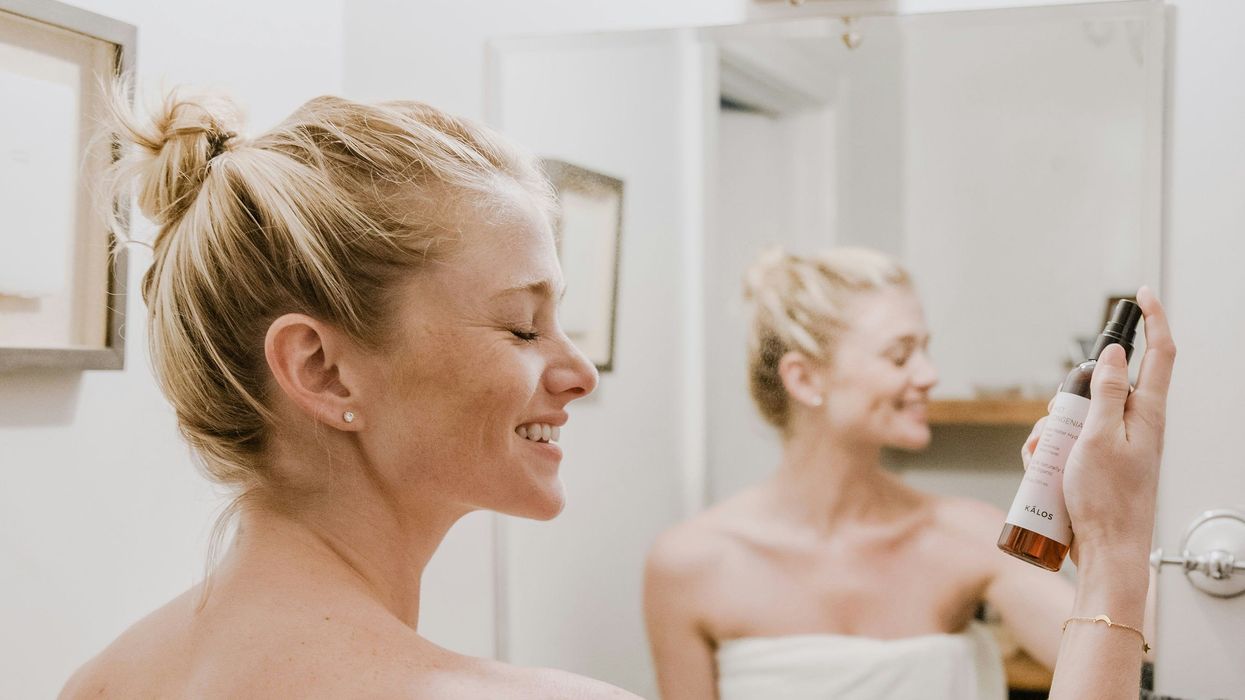 Woman spraying her face with skin care product