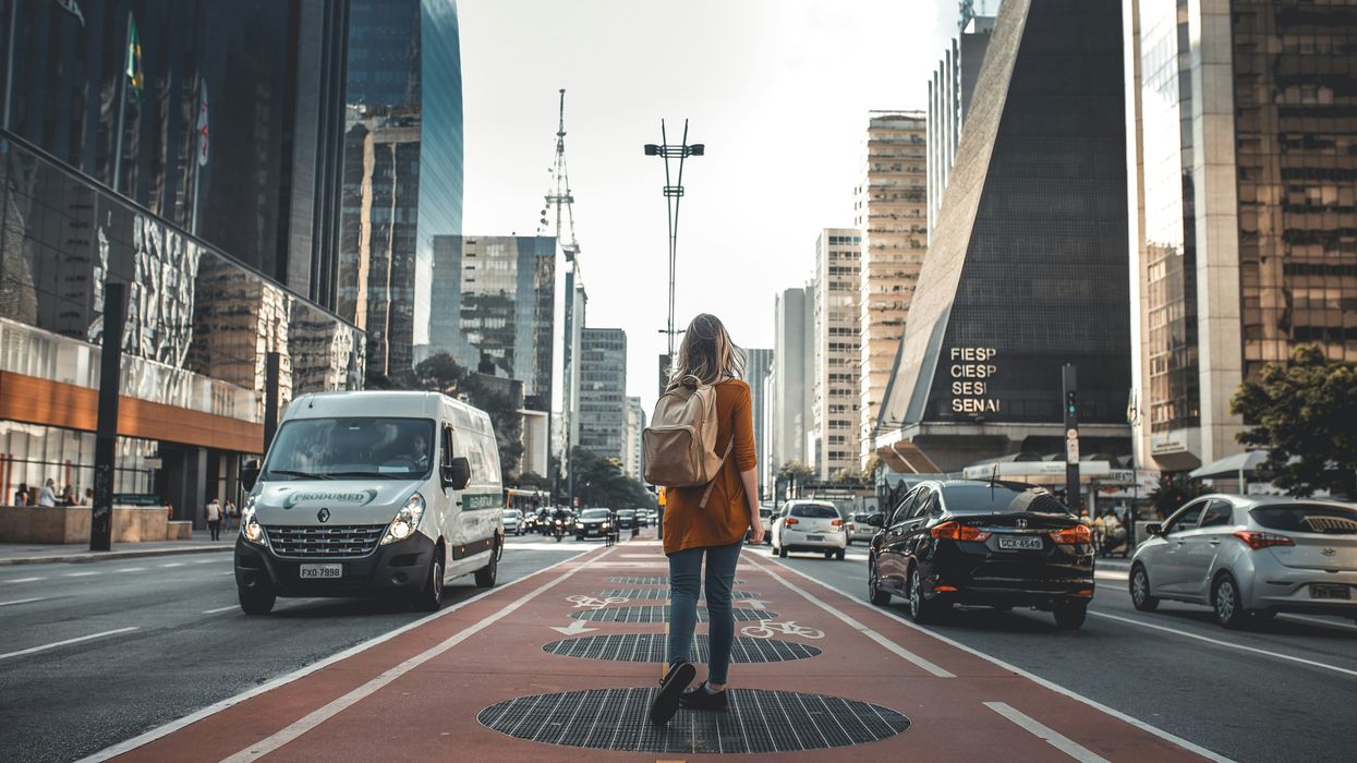 woman walking in middle of road with vehicles