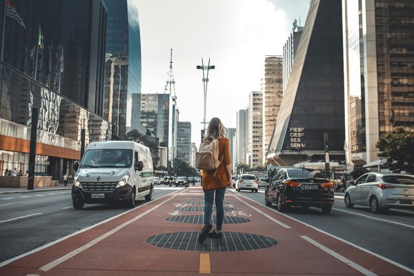 woman walking in middle of road with vehicles