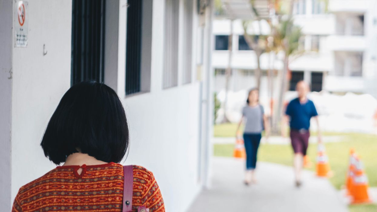 Woman walling with a bag over her shoulder and a couple walking towards her.