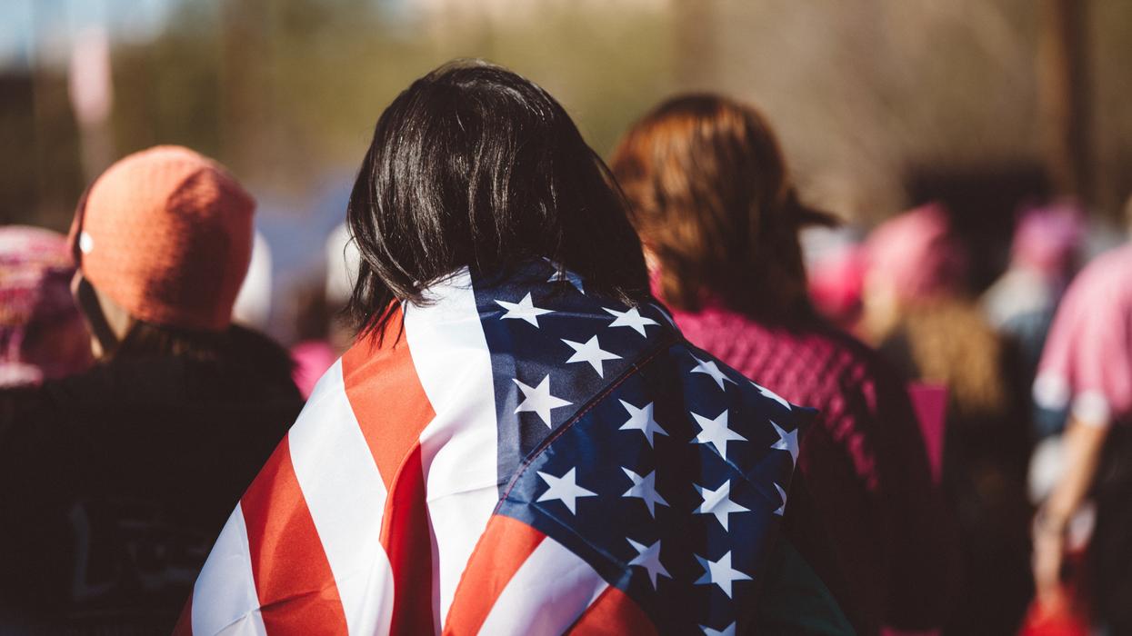 Woman with American flag wrapped around her shoulders