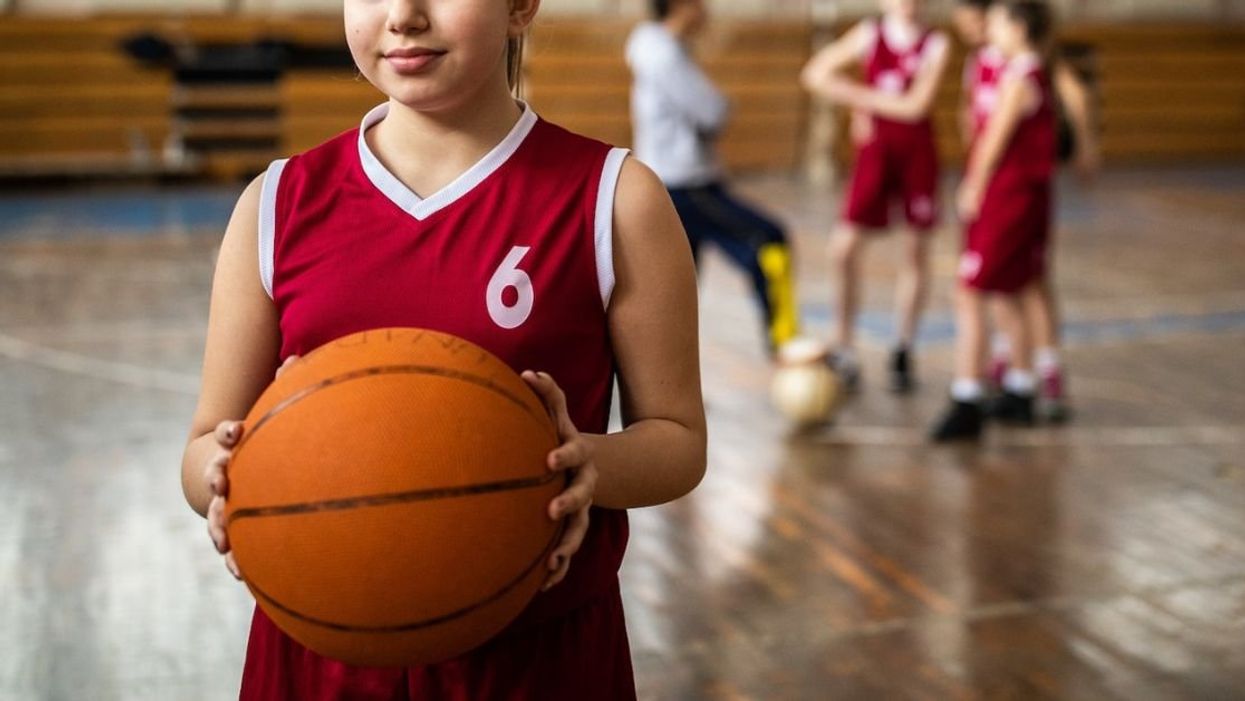 Young female student holding a basketball on the court