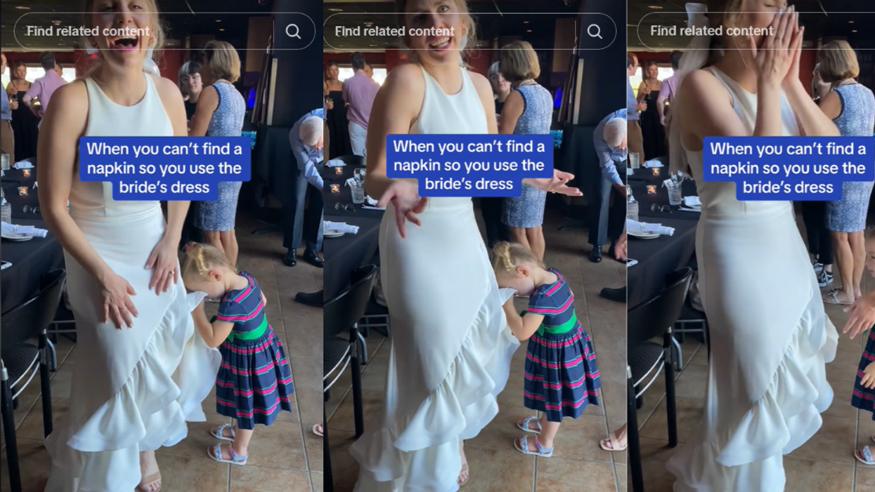Young girl wiping her face on the bride's dress